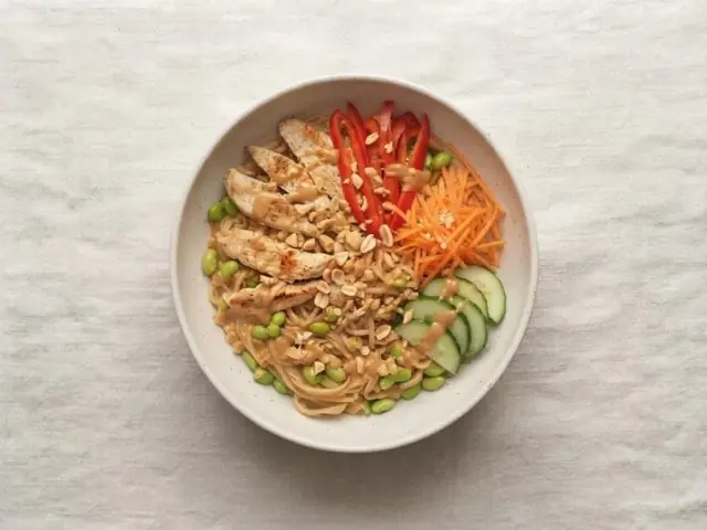 Peanut chicken noodle bowl with red pepper, carrot and cucumber