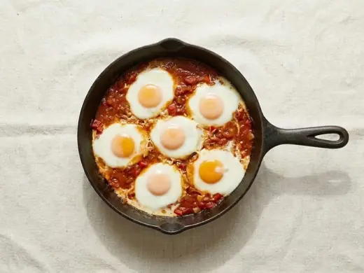 Six eggs cooking in the sauce