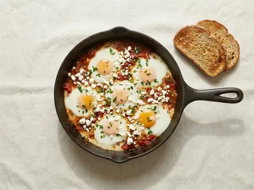 Finished shakshuka with feta, parsley and toast